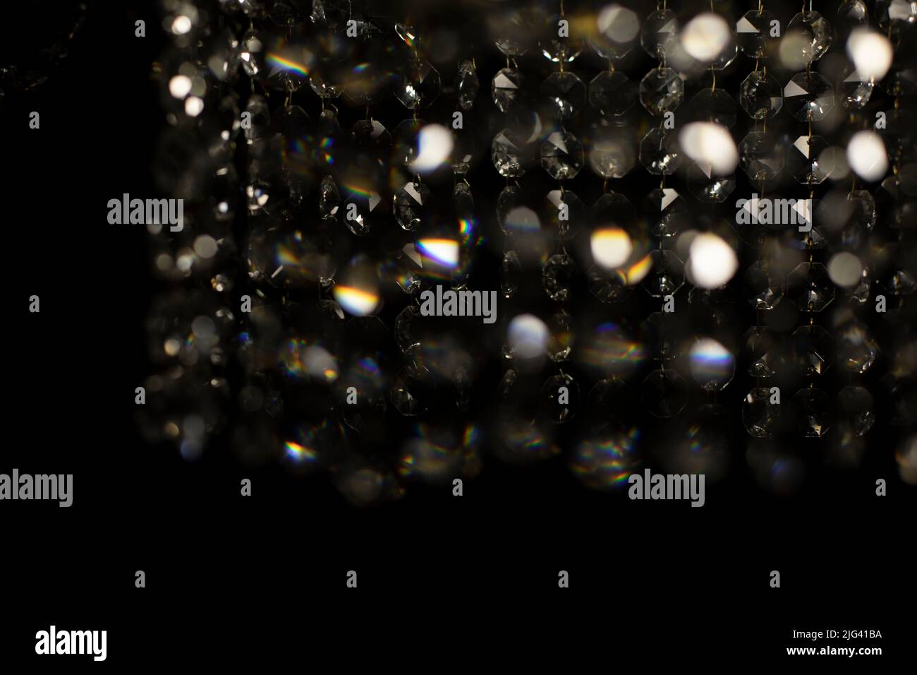 Tessuto di vetro trasparente in luce artificiale. Dettagli di lampadario in vetro scuro. Sfondo caotico di vetro in luce soffusa. Foto Stock