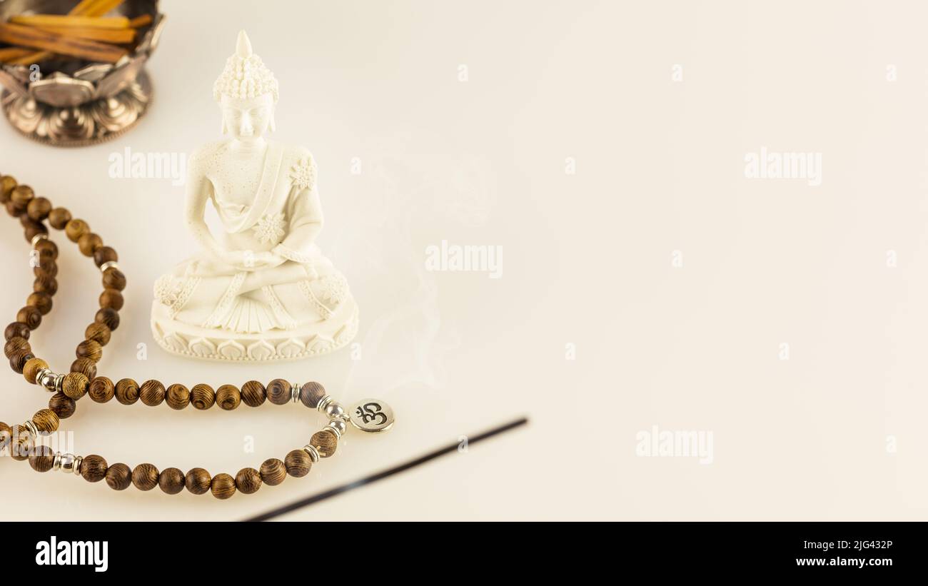 Statua di Buddha, perle di preghiera e bastoncini di aroma su sfondo bianco con spazio per la copia. Procedura rituale, guarigione e meditazione della spa asiatica. Guarigione energetica Foto Stock