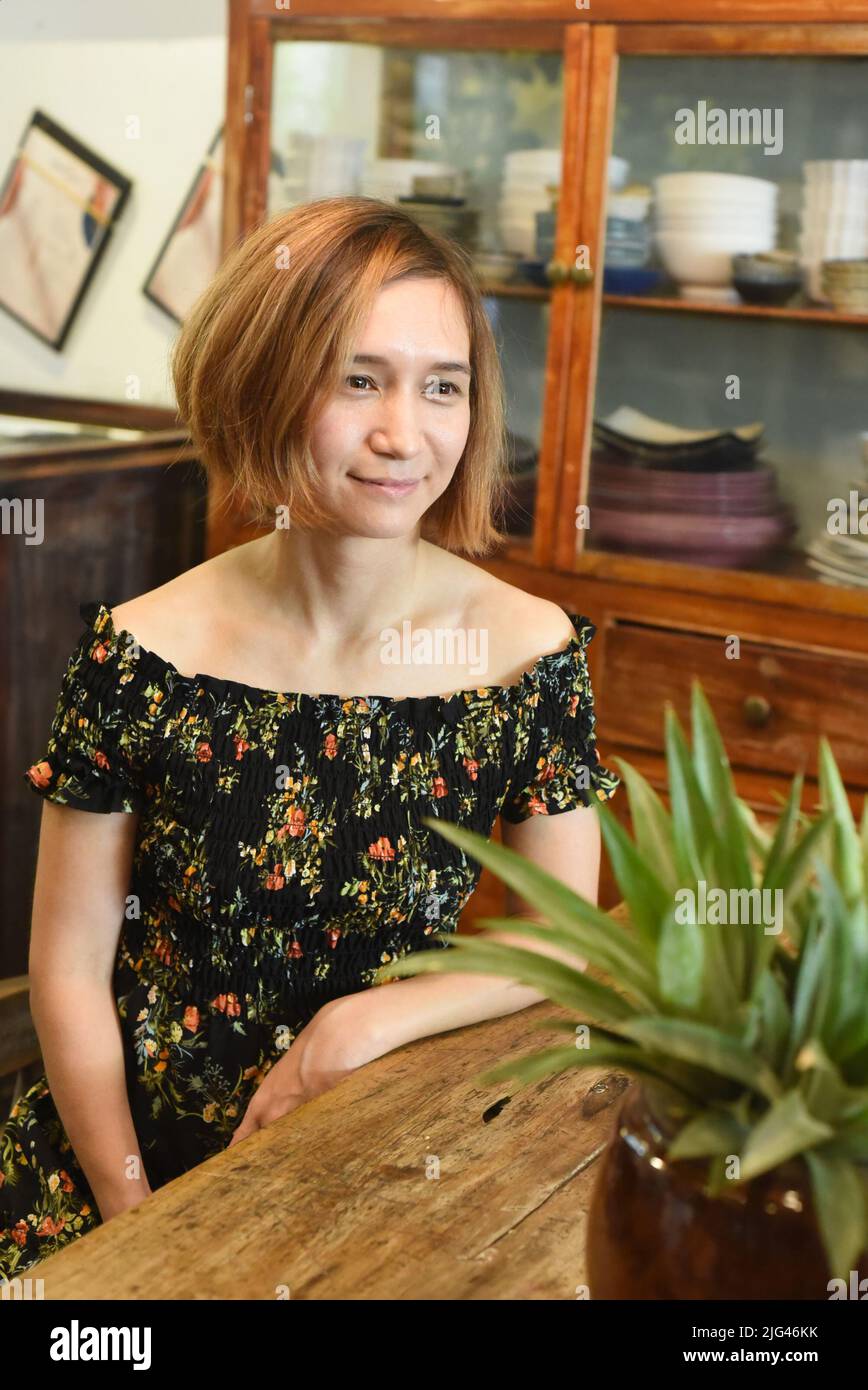 Una giovane donna seduta a tavola in legno in una caffetteria Foto Stock