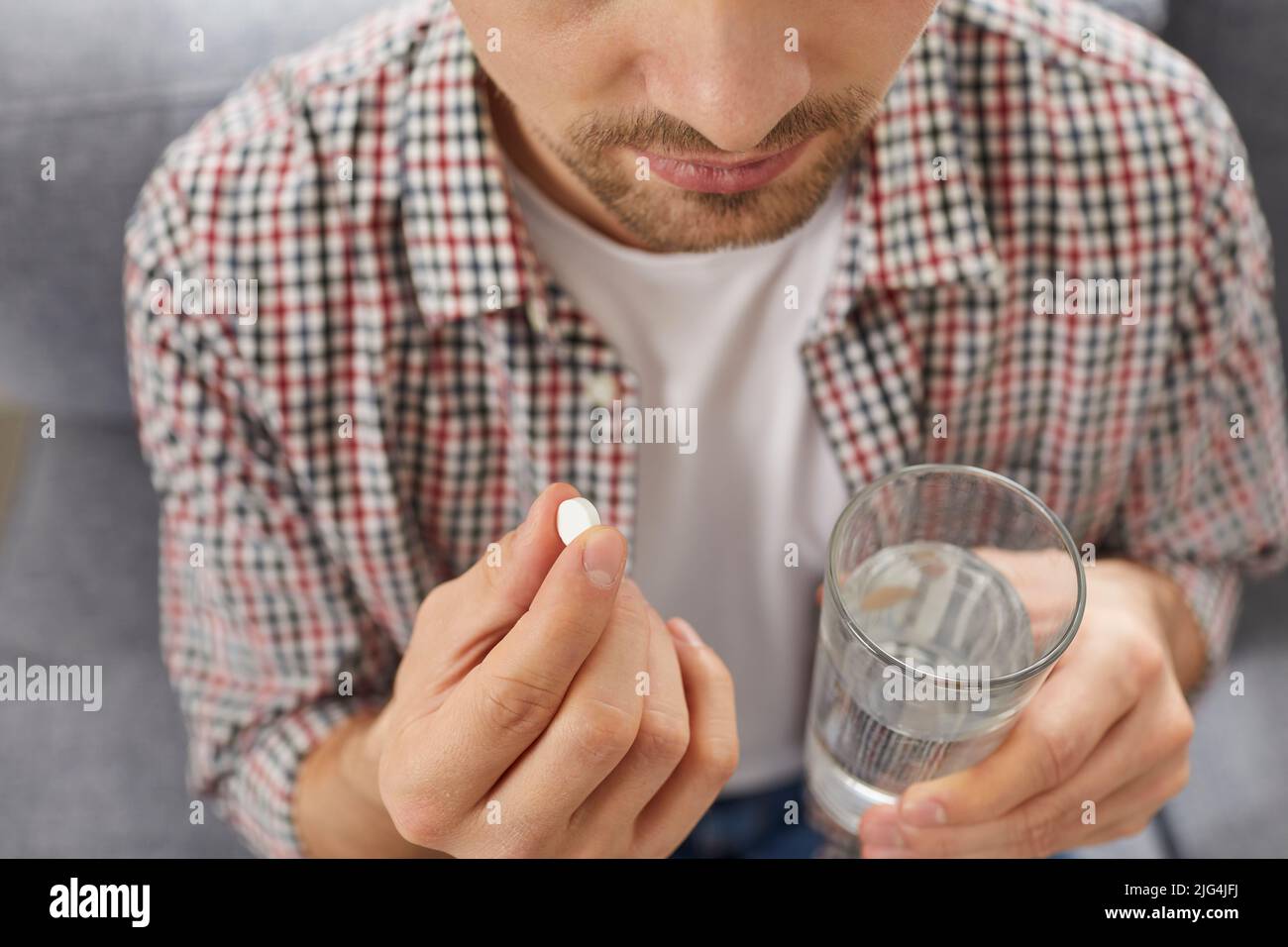 Malato giovane uomo beve pillola al mattino per alleviare il dolore o per rafforzare l'immunità. Foto Stock