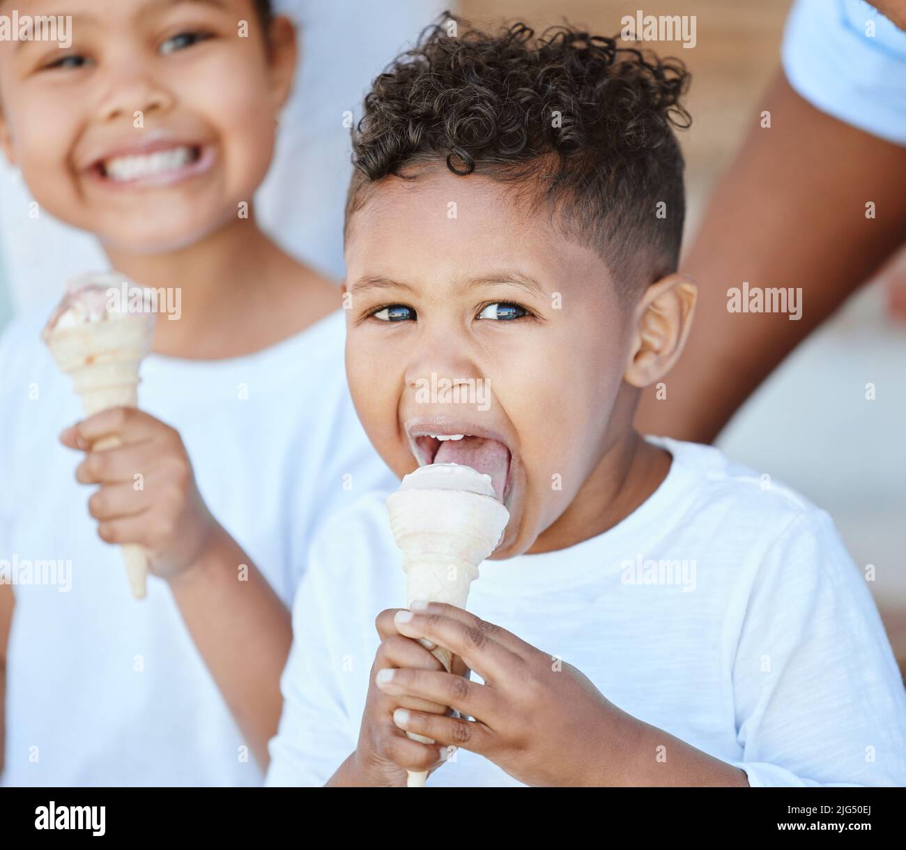 Dolce per i bambini. Shot di un adorabile ragazzo e ragazza che mangiano un cono gelato mentre si siede all'esterno. Foto Stock