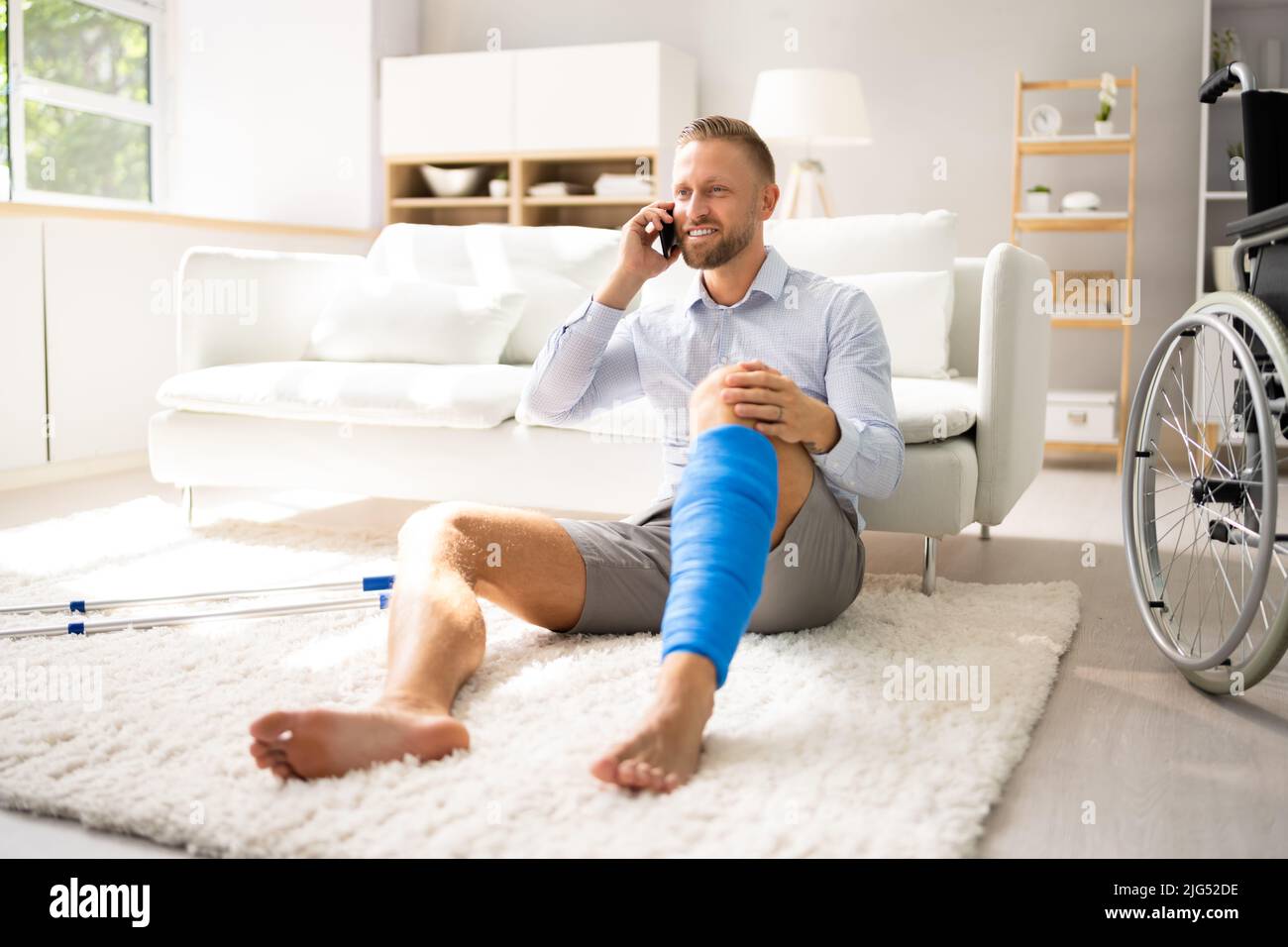 Uomo con lesioni alle gambe utilizzando stampelle a casa Foto Stock