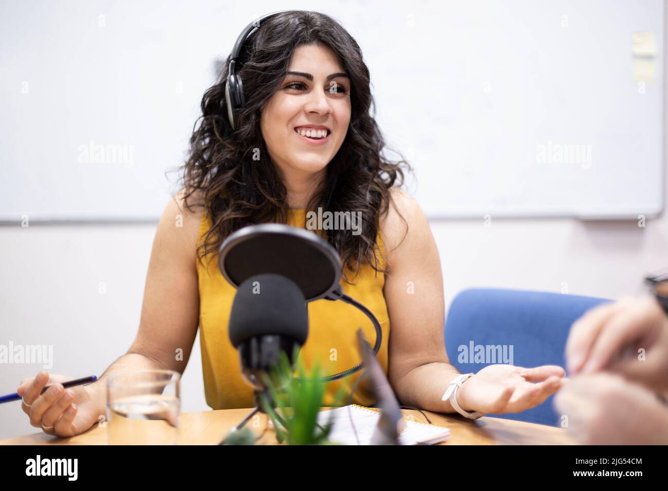 Sorridente giovane donna caucasica durante la trasmissione dal vivo. Annunciatore radio, ospite talk show, intervistatore. Foto Stock