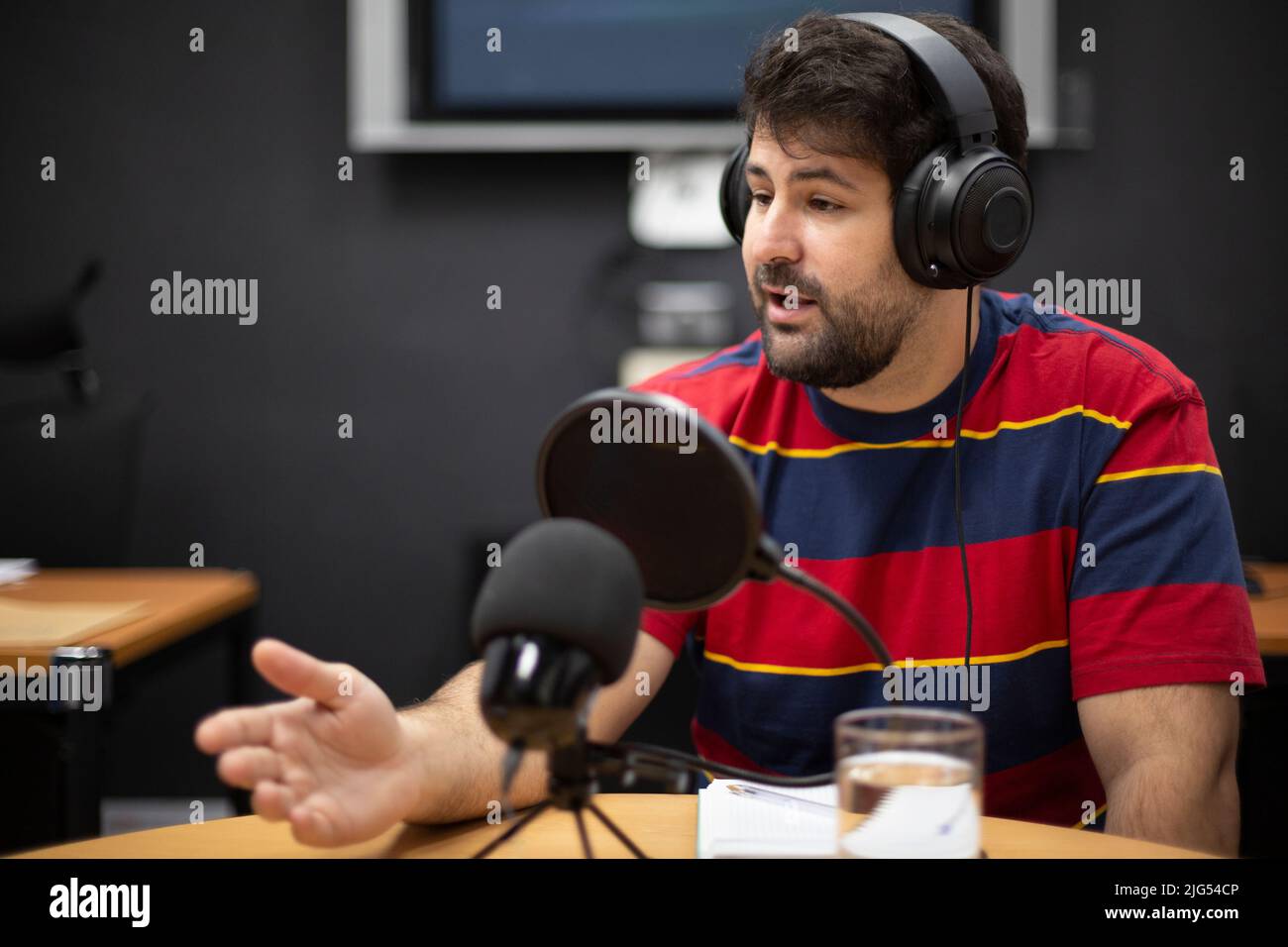 Giovane uomo caucasico durante la trasmissione dal vivo di un programma radiofonico. Spazio per il testo. Foto Stock