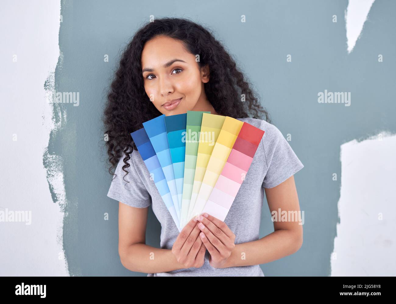 Che colore posso aggiungere per complimentarmi con questo. Scatto di una donna che tiene in piedi i campioni di colore mentre si alza contro una parete dipinta. Foto Stock