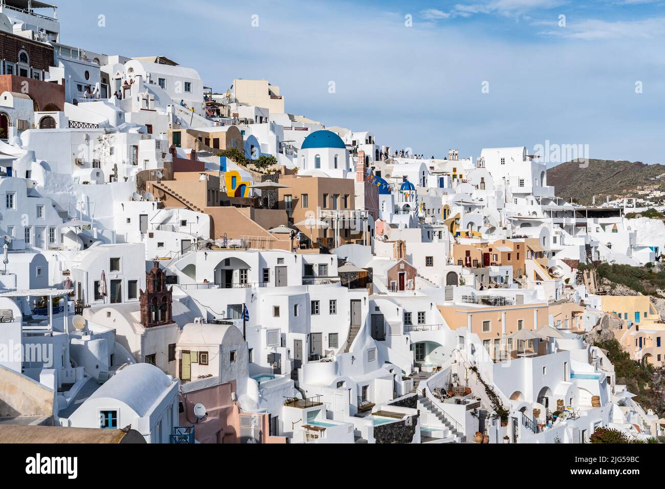Vista panoramica della città di Oia a Santorini con case dipinte di bianco e una piccola chiesa con cupole blu, Grecia Foto Stock