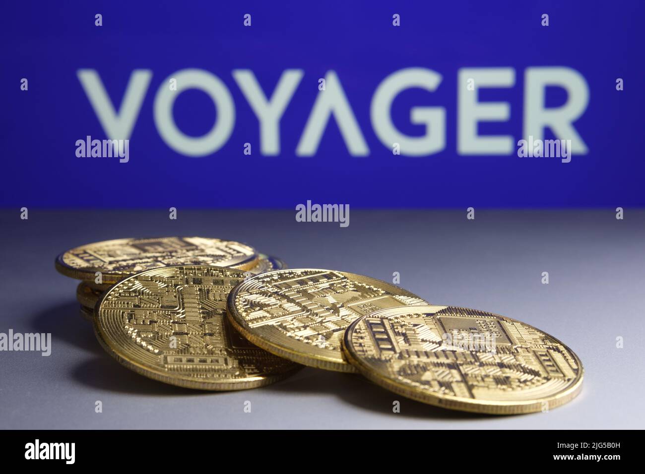 Catasta di cripto monete di fronte e blurred Voyager Digital Ltd logo della società su sfondo sfocato. Concetto di fallimento. Stafford, Regno Unito Foto Stock