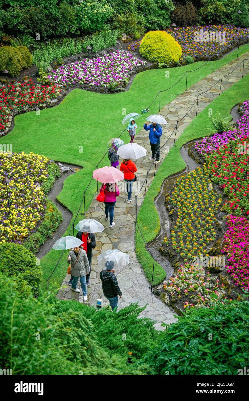 Persone con ombrelloni, Sunken Garden, Butchart Gardens, Brentwood Bay, Greater Victoria, British Columbia, Canada Foto Stock