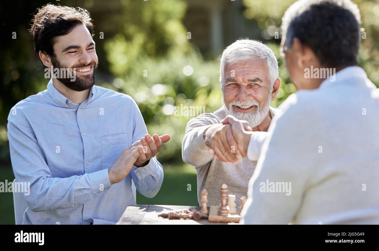 Gli amici mettono il compagno in check mate. Colpo di un gruppo di uomini che giocano una partita di scacchi fuori. Foto Stock