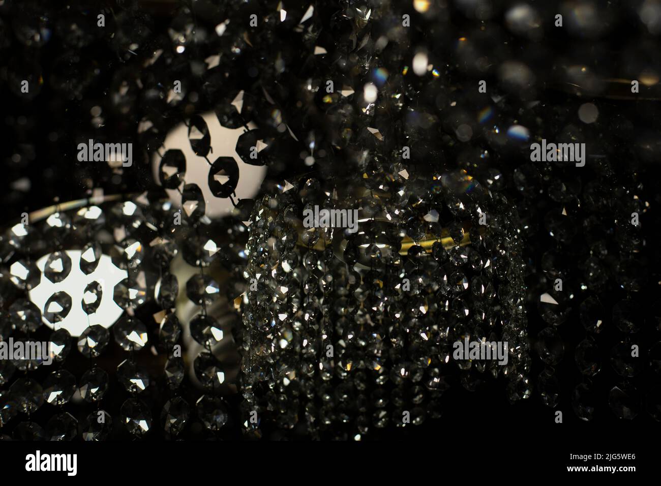 Tessuto di vetro trasparente in luce artificiale. Dettagli di lampadario in vetro scuro. Sfondo caotico di vetro in luce soffusa. Foto Stock