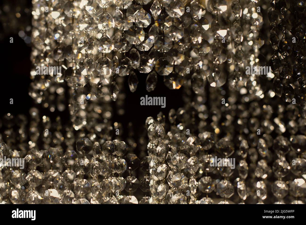 Tessuto di vetro trasparente in luce artificiale. Dettagli di lampadario in vetro scuro. Sfondo caotico di vetro in luce soffusa. Foto Stock