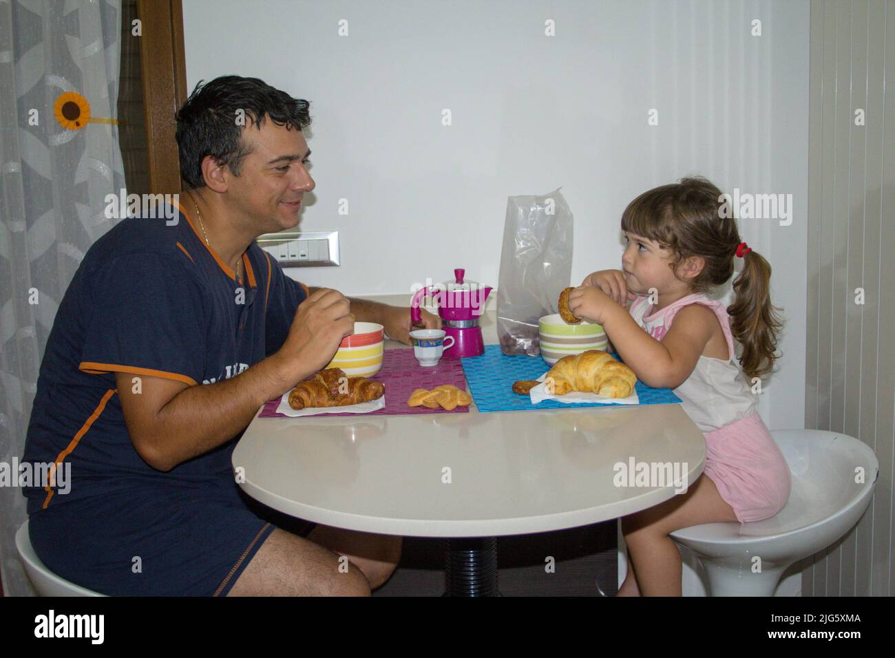 Immagine di un giovane papà con la figlia che sorride mentre fanno colazione la mattina. La giusta motivazione ed energia per affrontare la giornata Foto Stock