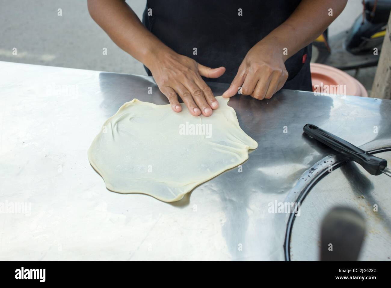 Impastare a mano l'impasto per preparare Roti crudi. Foto Stock