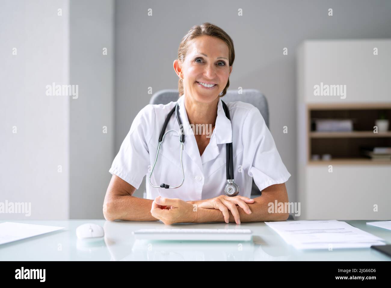 Ritratto di una donna felice medico con stetoscopio sulla scrivania Foto Stock