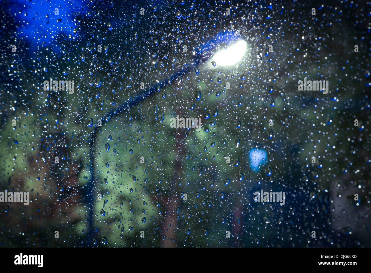 Sfondo notturno, lanterna, gocce di pioggia sul muro, sfondo sfocato. Foto Stock