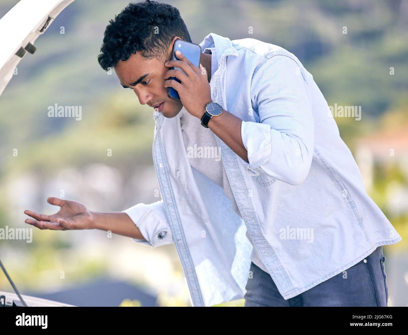 Im così confuso.... Scatto corto di un bel giovane uomo al telefono con assistenza stradale dopo aver subito un guasto del veicolo. Foto Stock