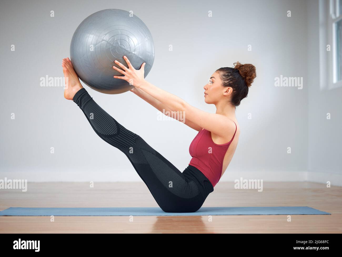 Pilates può essere impegnativo. Shot di una giovane donna che fa esercizi di nucleo utilizzando una palla di medicina. Foto Stock