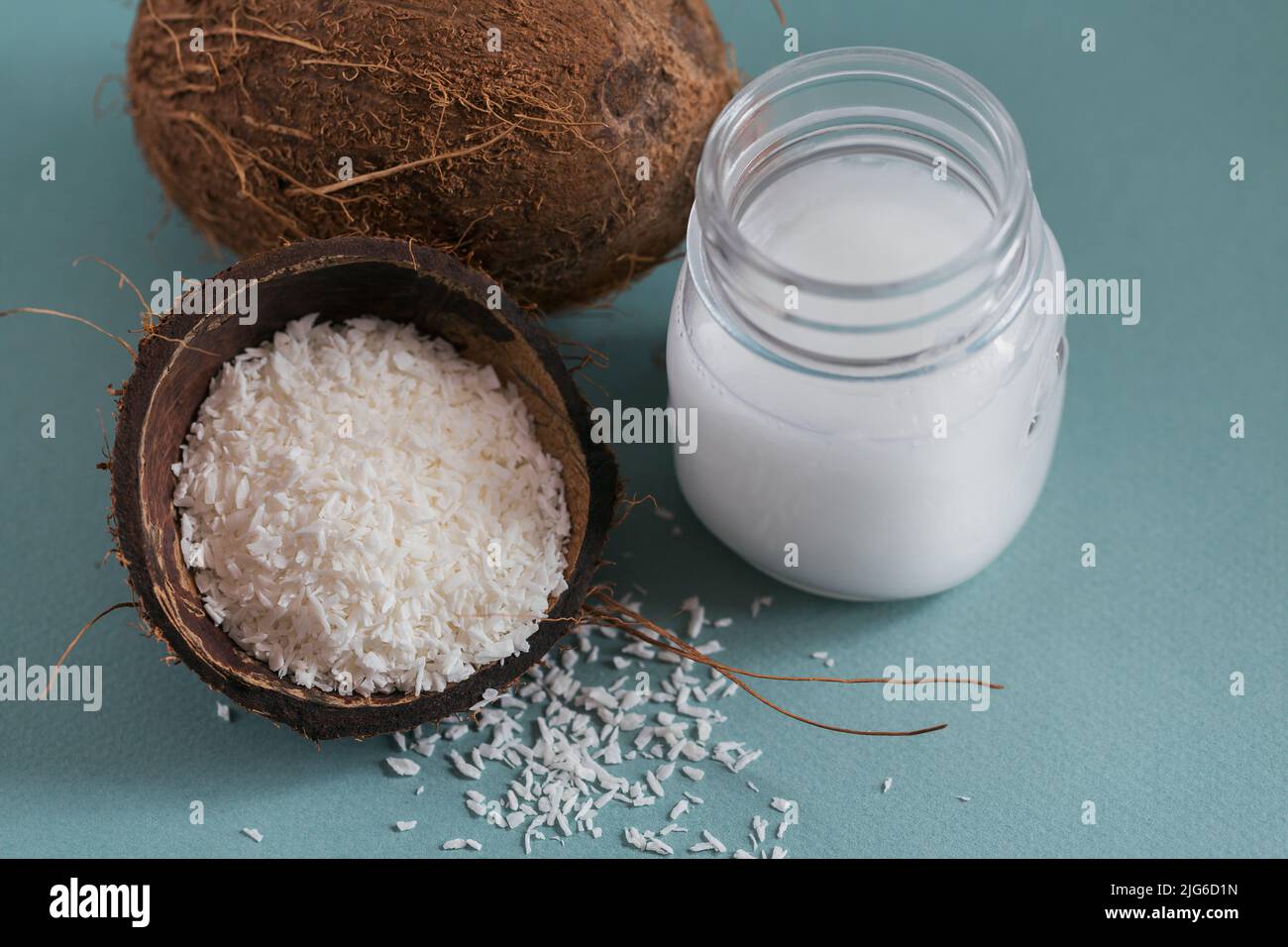 Cocco, fiocchi e olio di cocco in vaso su sfondo blu Foto Stock