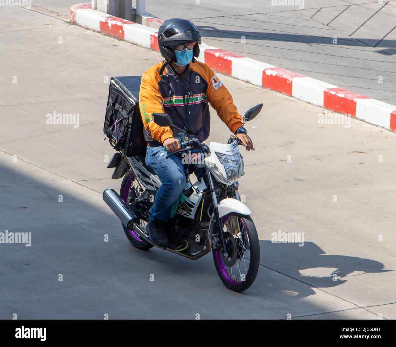 SAMUT PRAKAN, THAILANDIA, 28 marzo 2022, Un 7-undici uomo di consegna ride una moto con una scatola di consegna Foto Stock