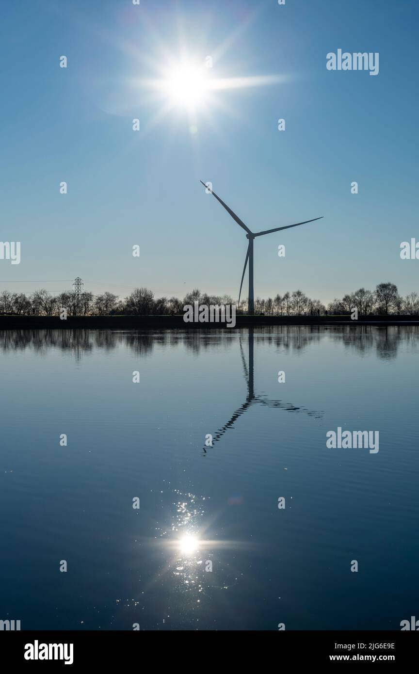 Cielo invernale blu e riflessi a Penyfan Pond, Blackwood, South Wales, UK, con silhouette a turbina eolica. Foto Stock
