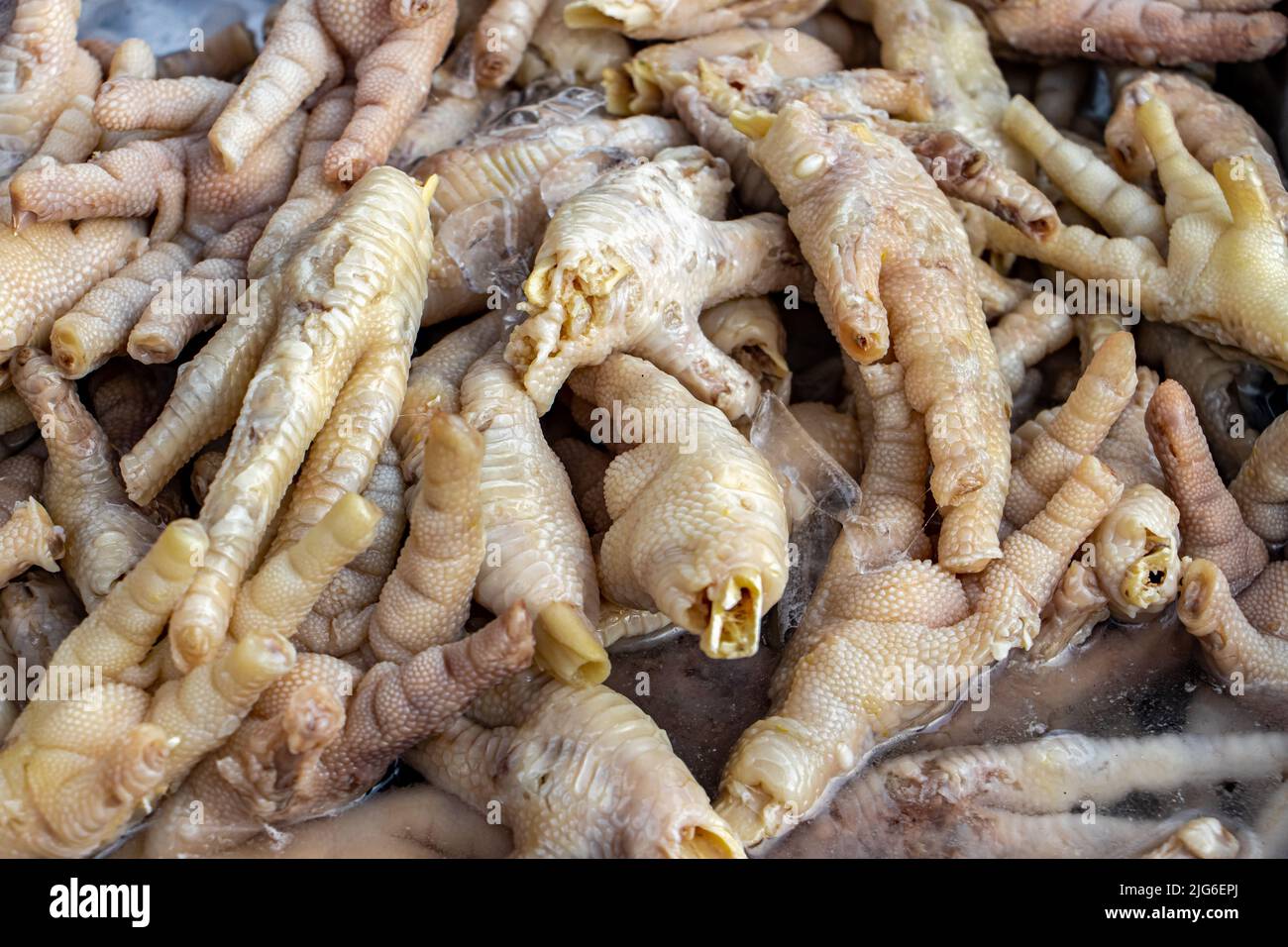 Un mucchio di artigli crudi di pollo in offerta in un mercato thailandese Foto Stock