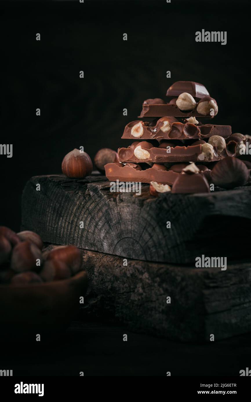 Mucchio di cioccolato al latte di nocciole e noci su sfondo scuro Foto Stock
