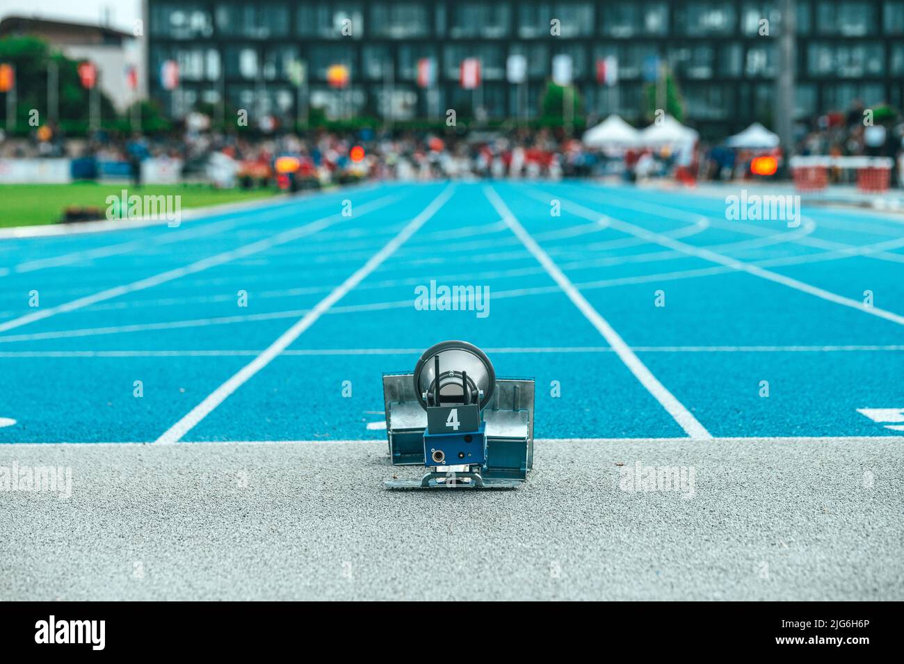 Gara su pista e campo, foto illustrativa. Blocchi di partenza e lo stadio di atletica in background. Pista da atletica blu, foto sportiva con posto f Foto Stock