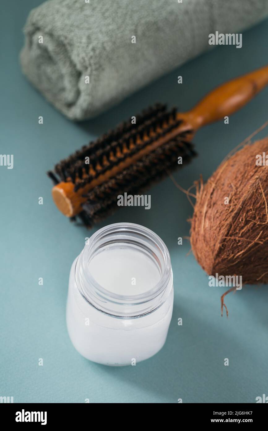 Olio di cocco in bottiglia con noci di cocco, asciugamano e spazzola per capelli Foto Stock