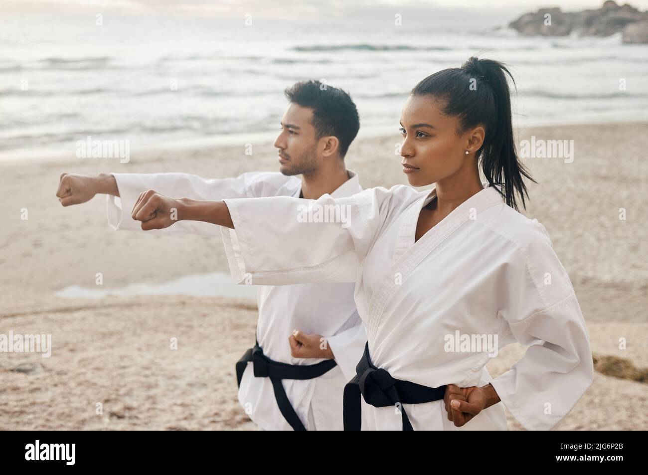 Puoi solo combattere il modo in cui ti fai pratica. Girato di due giovani artisti marziali che praticano il karate sulla spiaggia. Foto Stock