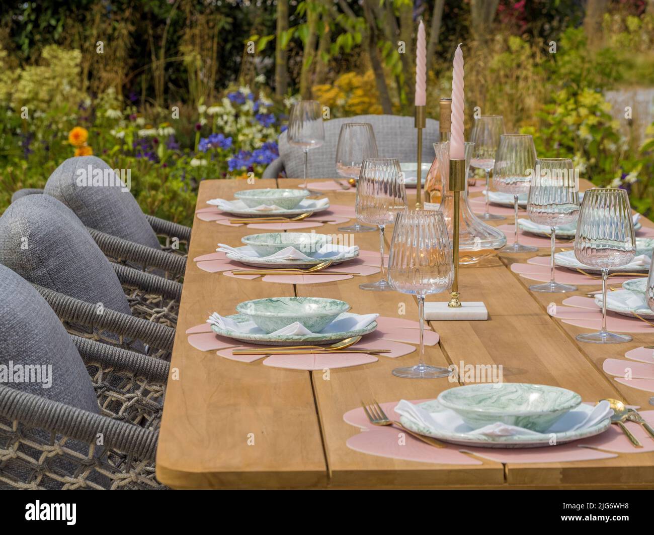 Tavolo da giardino in legno allestito per una cena in un giardino con spettacolo all'Hampton Court Palace Garden Festival. Londra. Foto Stock