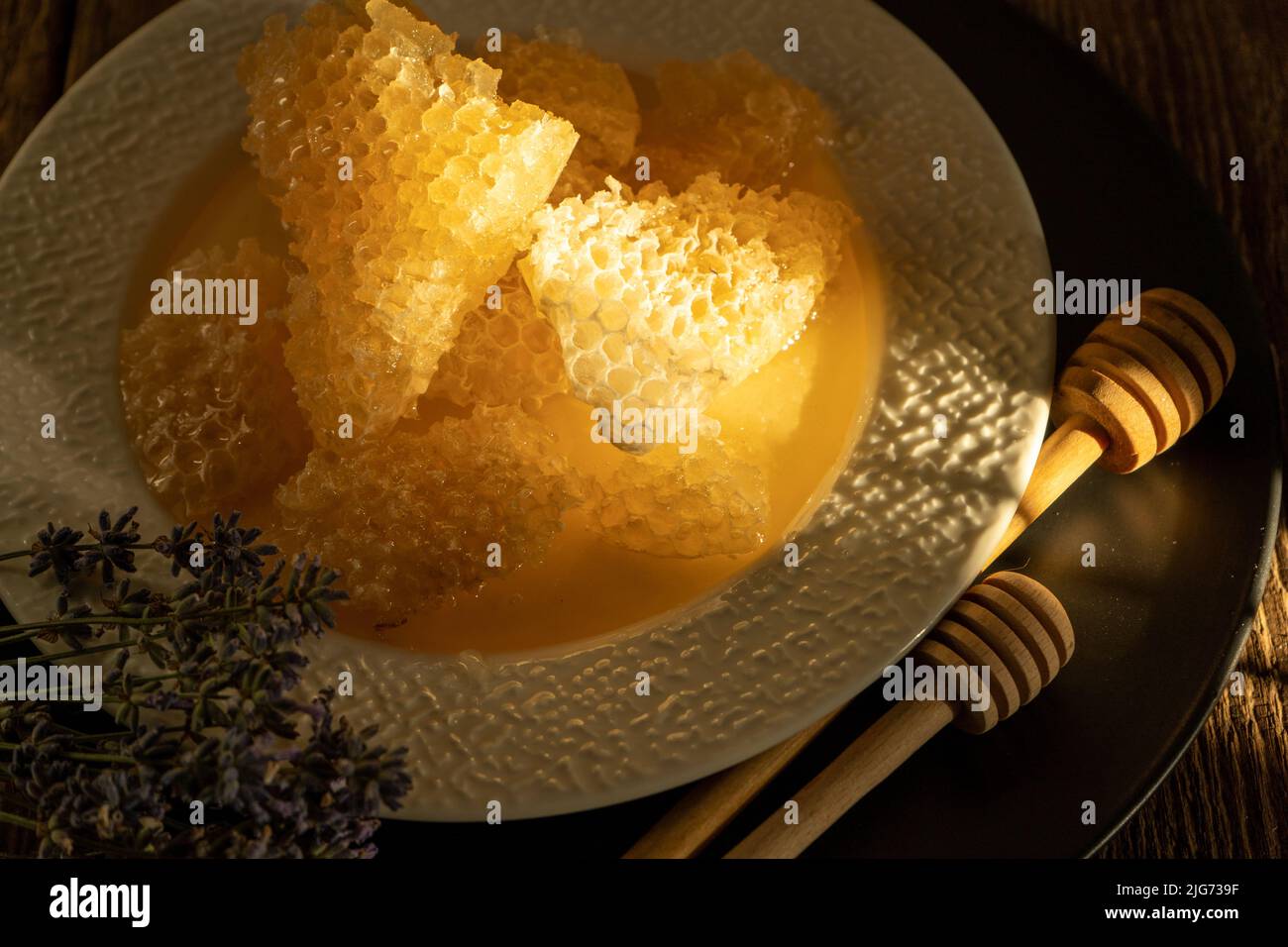 Miele e nido d'ape su un piatto bianco. Cibo dolce in una ciotola sul tavolo. Un prodotto dell'apicoltura. Fiore di lavanda. Foto Stock