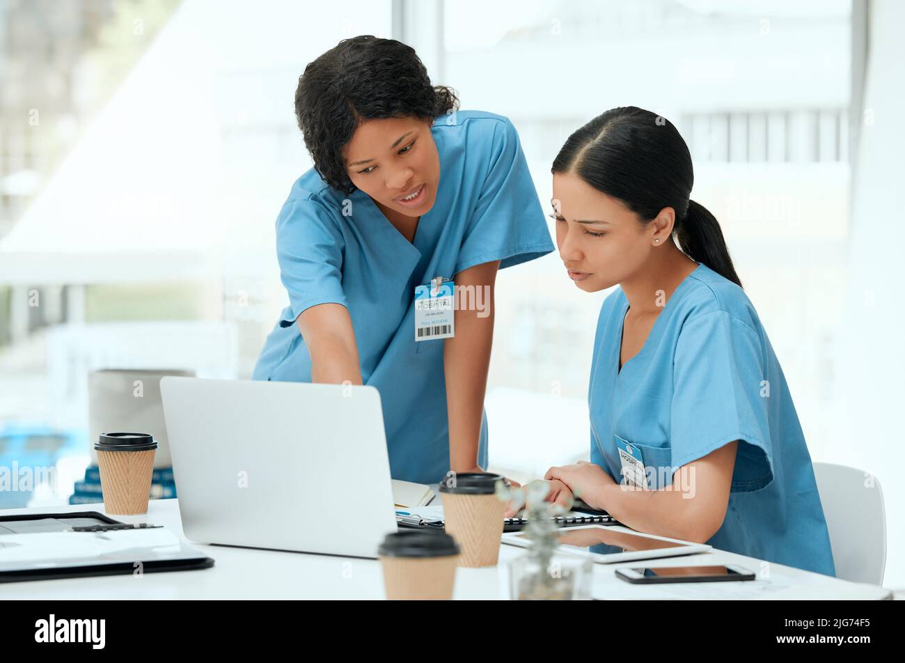 Lascia fare una certa ricerca. Scatto di due giovani medici donne utilizzando un computer portatile in un ospedale. Foto Stock