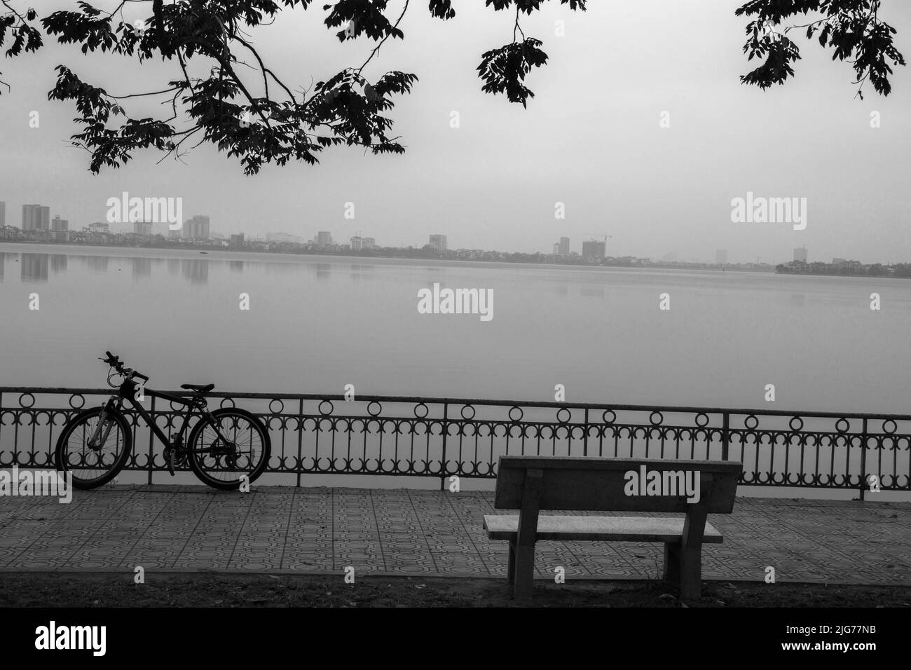 silhouette di bicicletta vicino al lago in nebbia Foto Stock