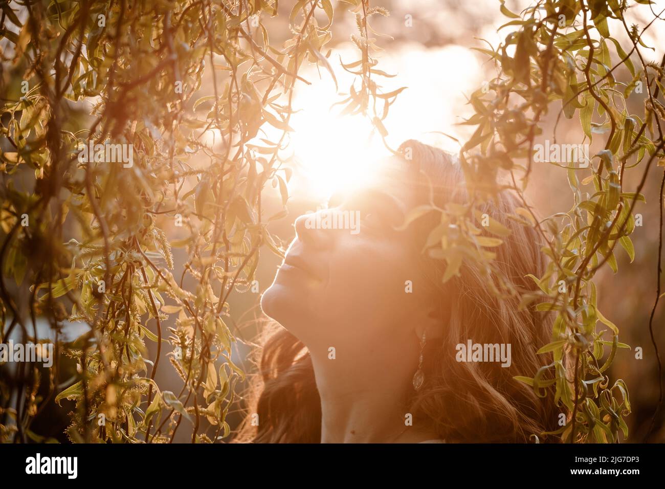 Bella donna romantica godendo la natura primaverile al tramonto. Ritratto in primo piano con trucco naturale Foto Stock