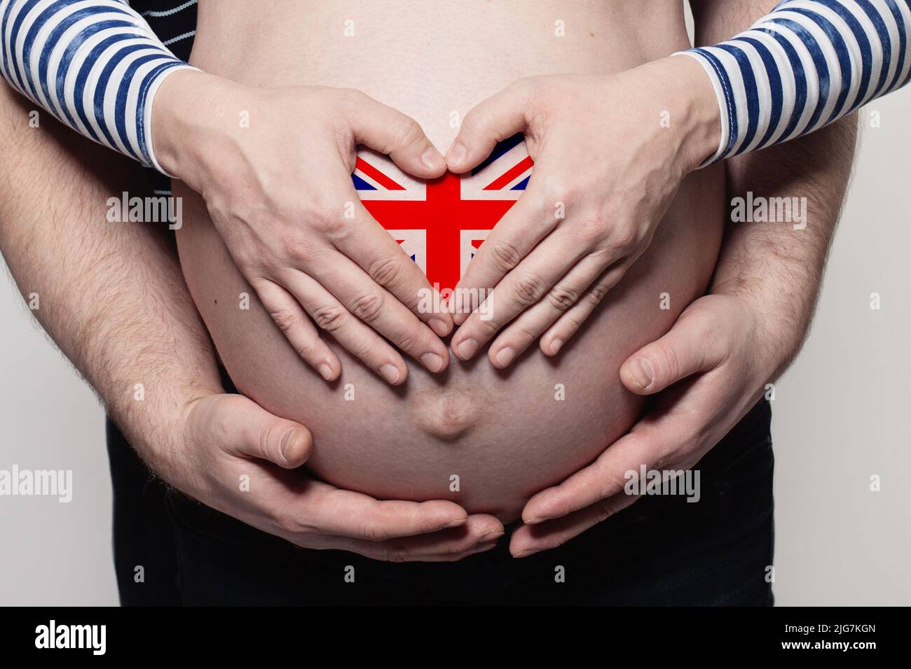 Concetto di famiglia inglese. Uomo che abbraccia il ventre e il cuore della donna incinta con i colori della bandiera del Regno Unito primo piano Foto Stock