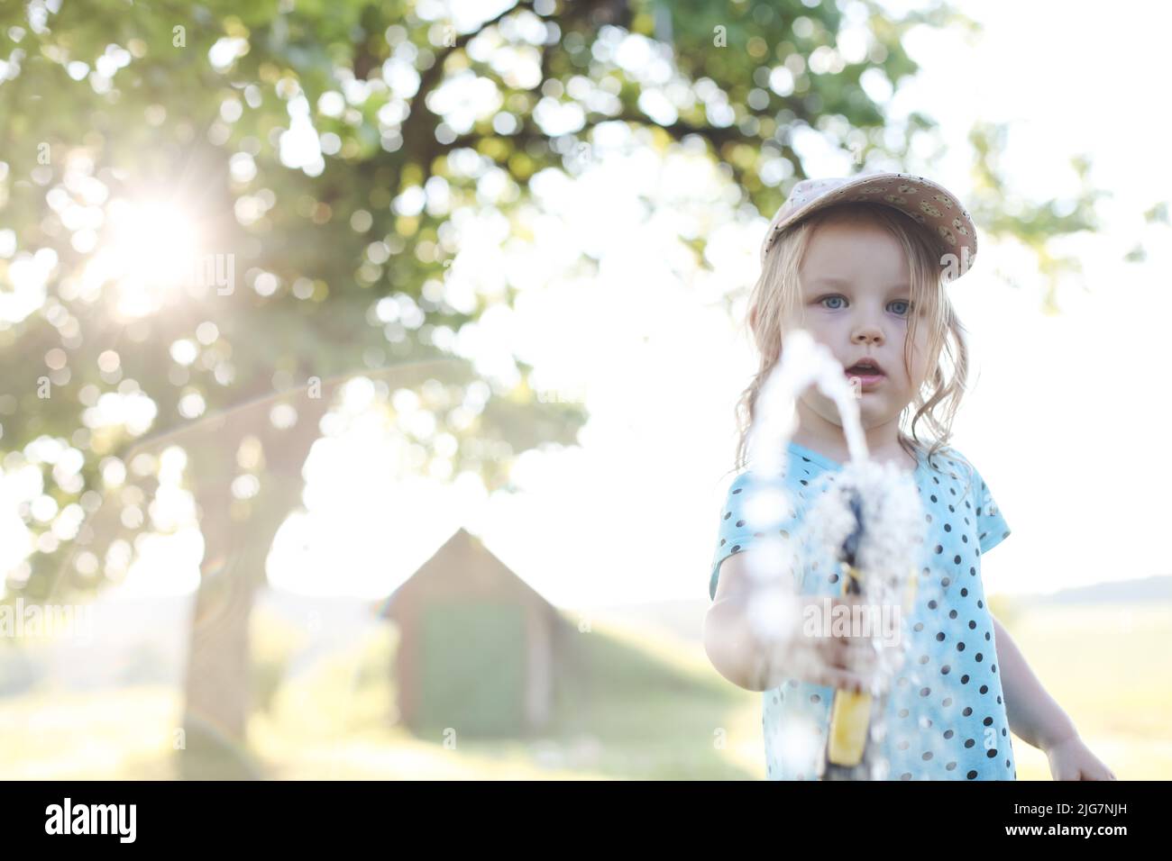 Adorabile bambina che gioca con una manichetta da giardino nella giornata estiva calda e soleggiata Foto Stock
