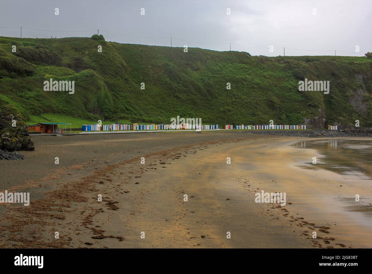 spiaggia con abbondanza di capanne e la montagna dietro Foto Stock