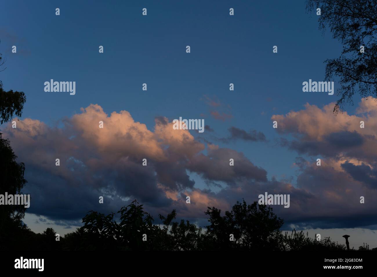 Nuvole di pioggia grandi e basse durante il tramonto Foto Stock