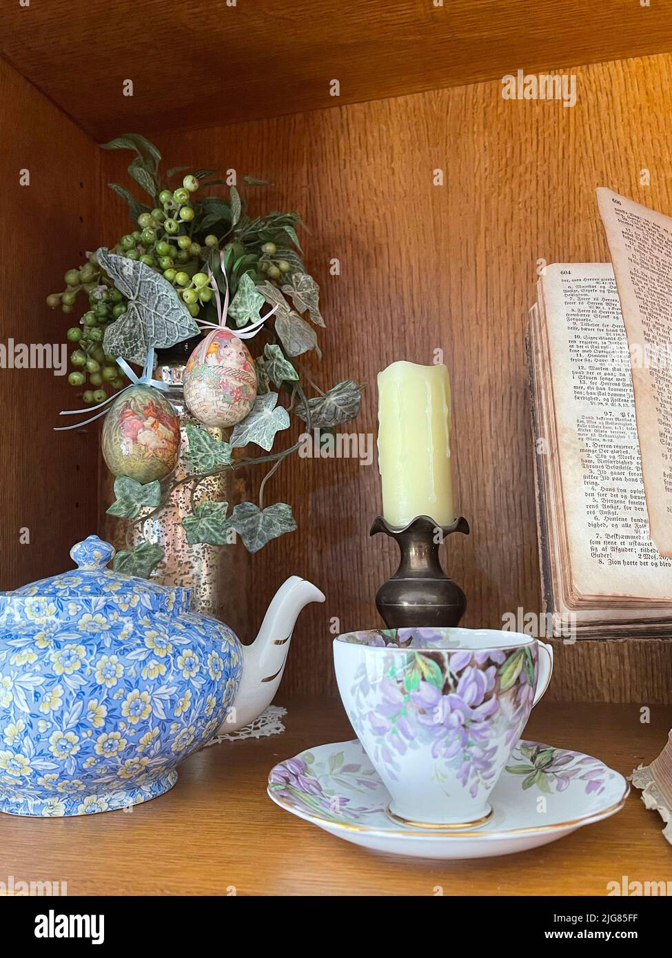 Un colpo verticale di una teiera floreale in porcellana e una tazza di caffè con decorazioni pasquali sullo sfondo Foto Stock