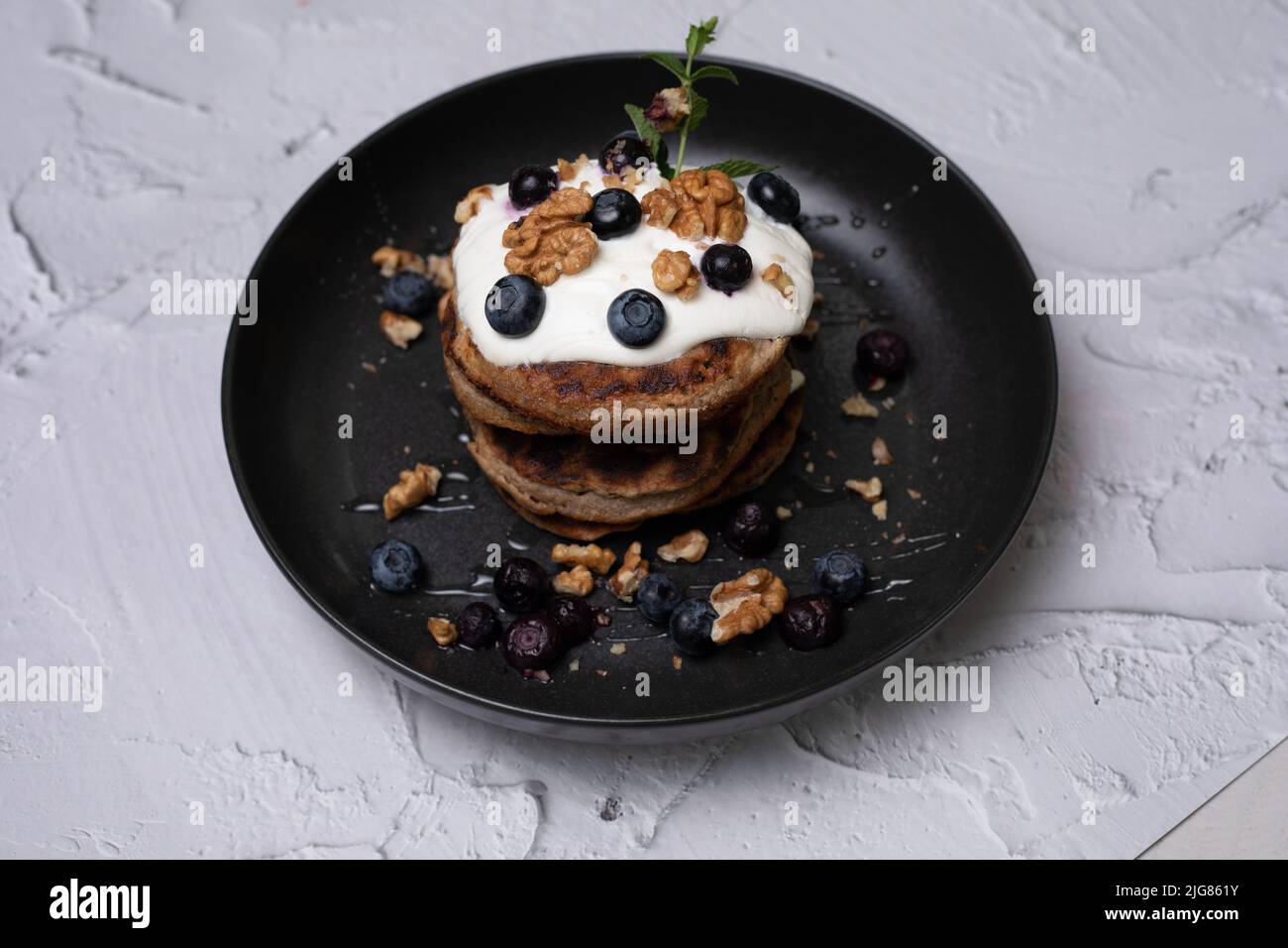 Colazione perfetta, pancake americani accatastati serviti su un tavolo di pietra nera. Deliziose frittelle americane impilate con mirtillo, da vicino, vista dall'alto. Foto Stock