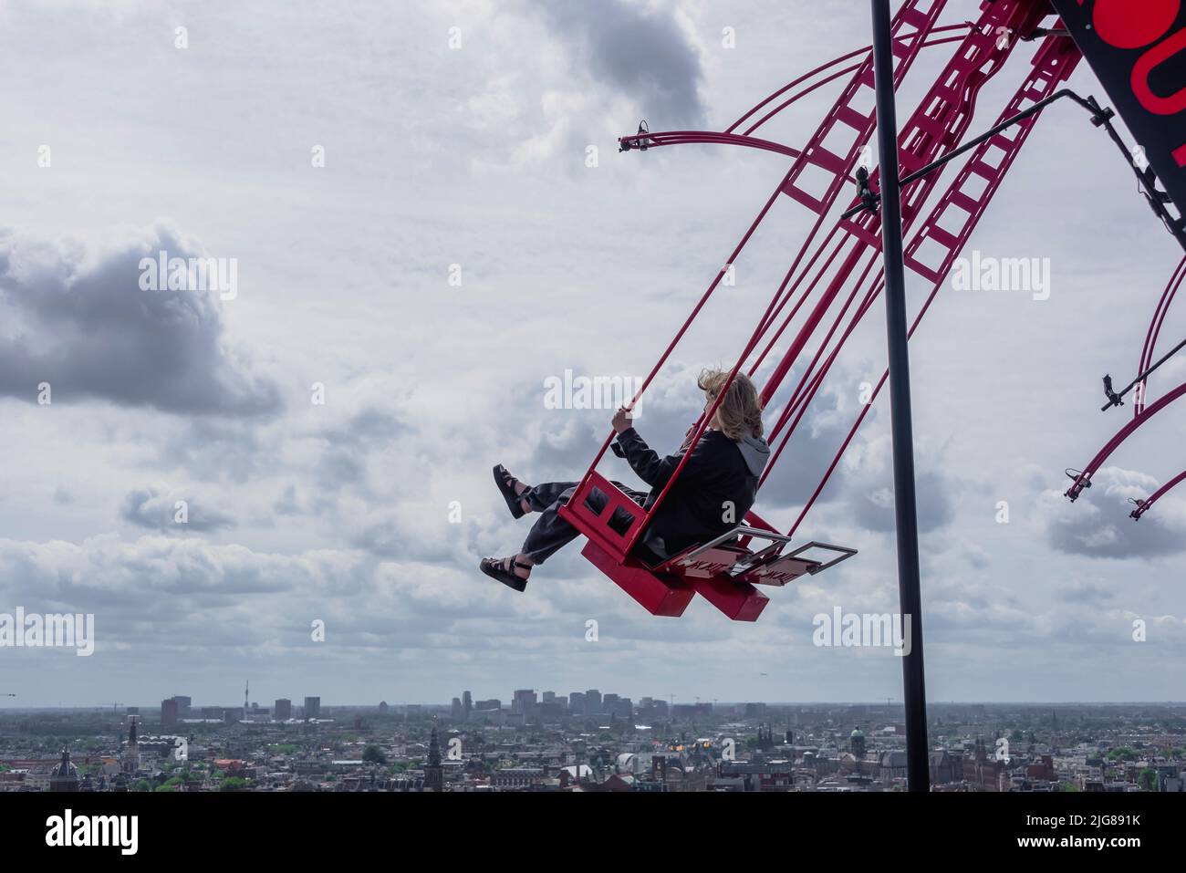 Paesi Bassi, Amsterdam: La giovane donna oscilla ad un'altezza di 100 metri sopra Amsterdam. "Over the Edge" è l'altalena più alta d'Europa e una popolare attrazione turistica nel quartiere Noord di Amsterdam. Foto Stock