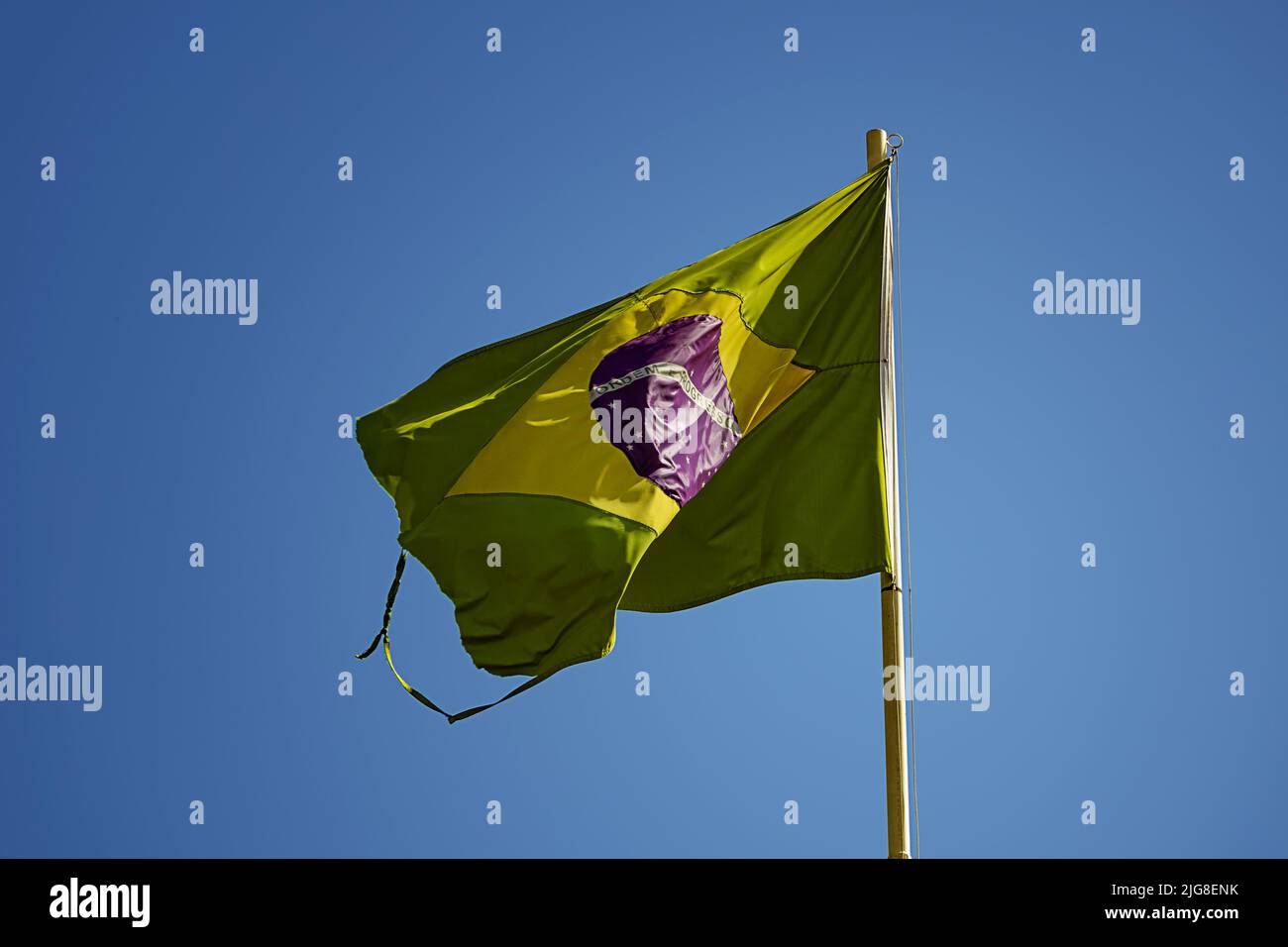 Goiania, Goiás, Brasile – 08 luglio 2022: Una vecchia bandiera brasiliana, strappata e sfilacciata, sventolando nel vento. Foto Stock