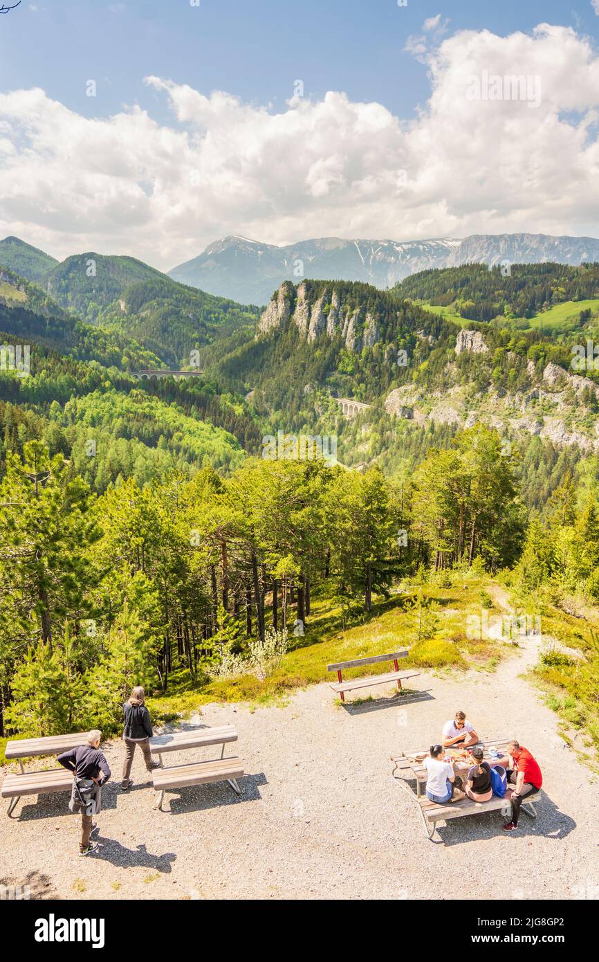 Semmering, Vista da '20-Schilling-Blick' (20 Scilling view) del Semmeringbahn (Semmering Railway) con il viadotto Kalte-Rinne-Viadukt, parete Polleroswand, montagna Rax, treno, tavolo da picnic, Persone nelle Alpi di Vienna, bassa Austria, Austria Foto Stock