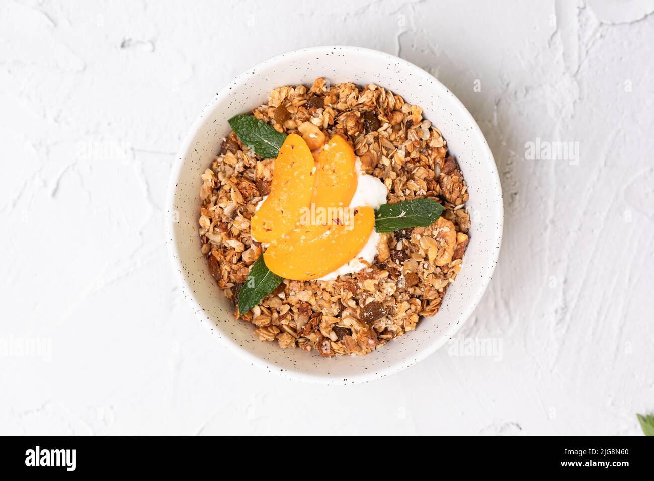 Ciotola di granola fatta in casa con yogurt e pesca fresca su sfondo bianco dalla vista dall'alto. Superfoood Foto Stock