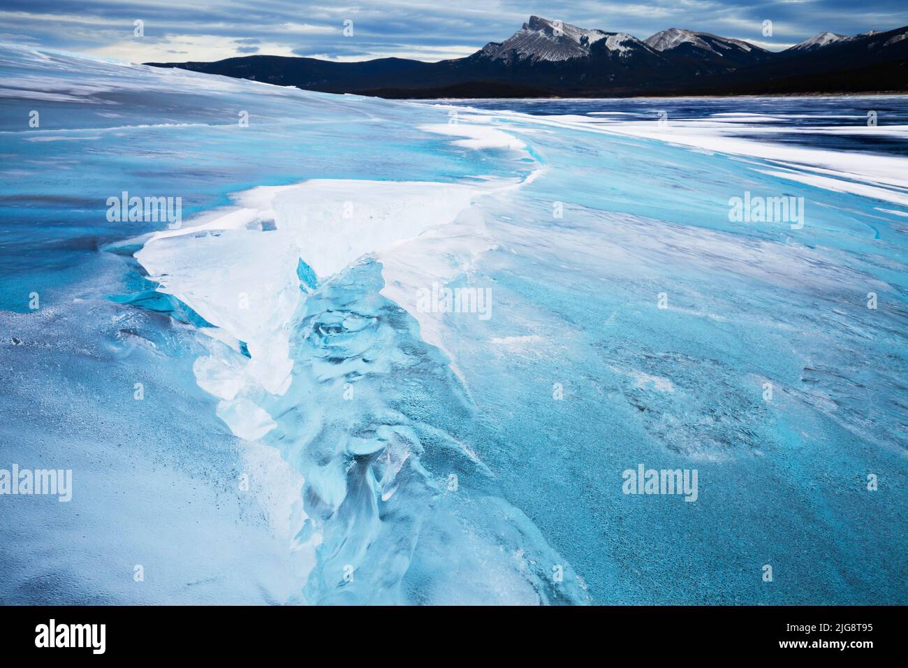 Incrinature nel ghiaccio con picco di Kista in background, Lago di Abramo, Alberta, Canada Foto Stock