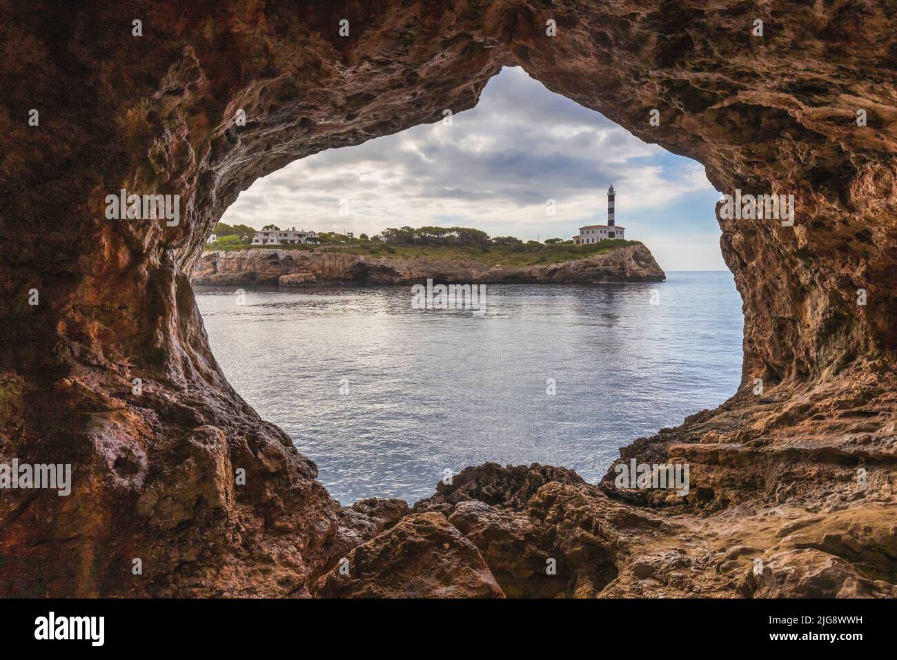 Spagna, Isole Baleari, Maiorca, distretto di Felanitx, Portocolom. SA Cova Foradada, arco naturale di roccia di fronte al faro di Punta de Ses Crestes Foto Stock