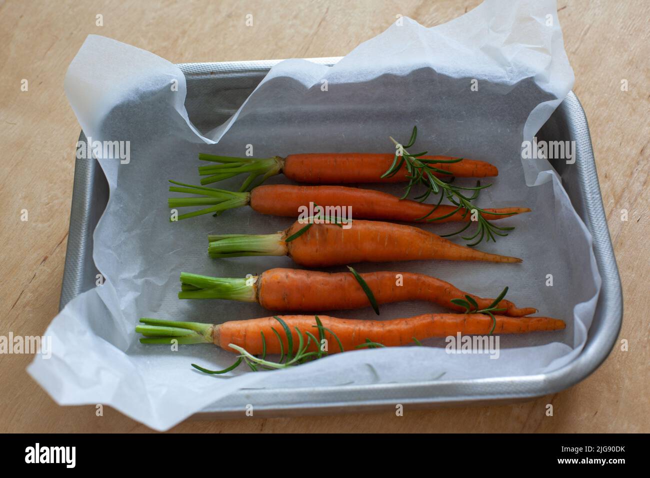 Carota intera giovane con verdure in teglia da forno Foto Stock