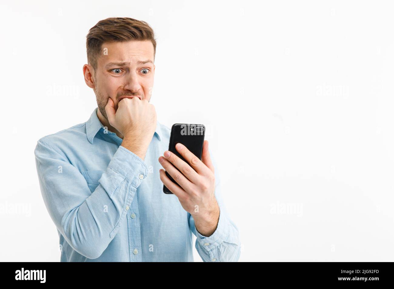 Un uomo con uno smartphone è in un panico a causa della caduta del mercato della criptovaluta. L'inflazione ha fatto diminuire i risparmi. La caduta del mercato patrimoniale Foto Stock