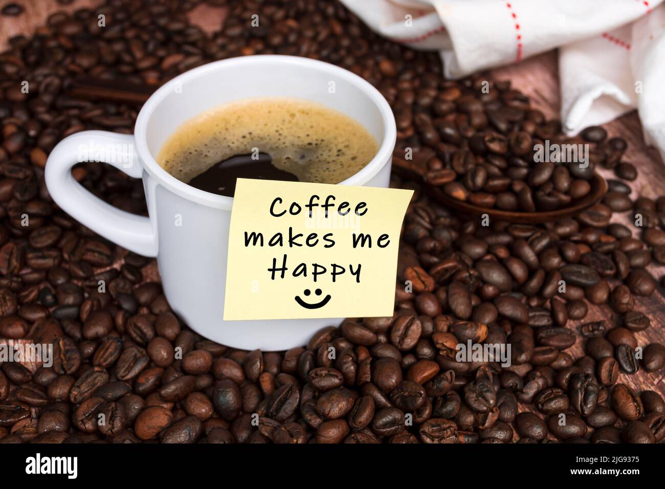Citazione motivazionale sulla nota appiccicosa gialla con caffè su sfondo di legno - il caffè mi rende felice. Foto Stock