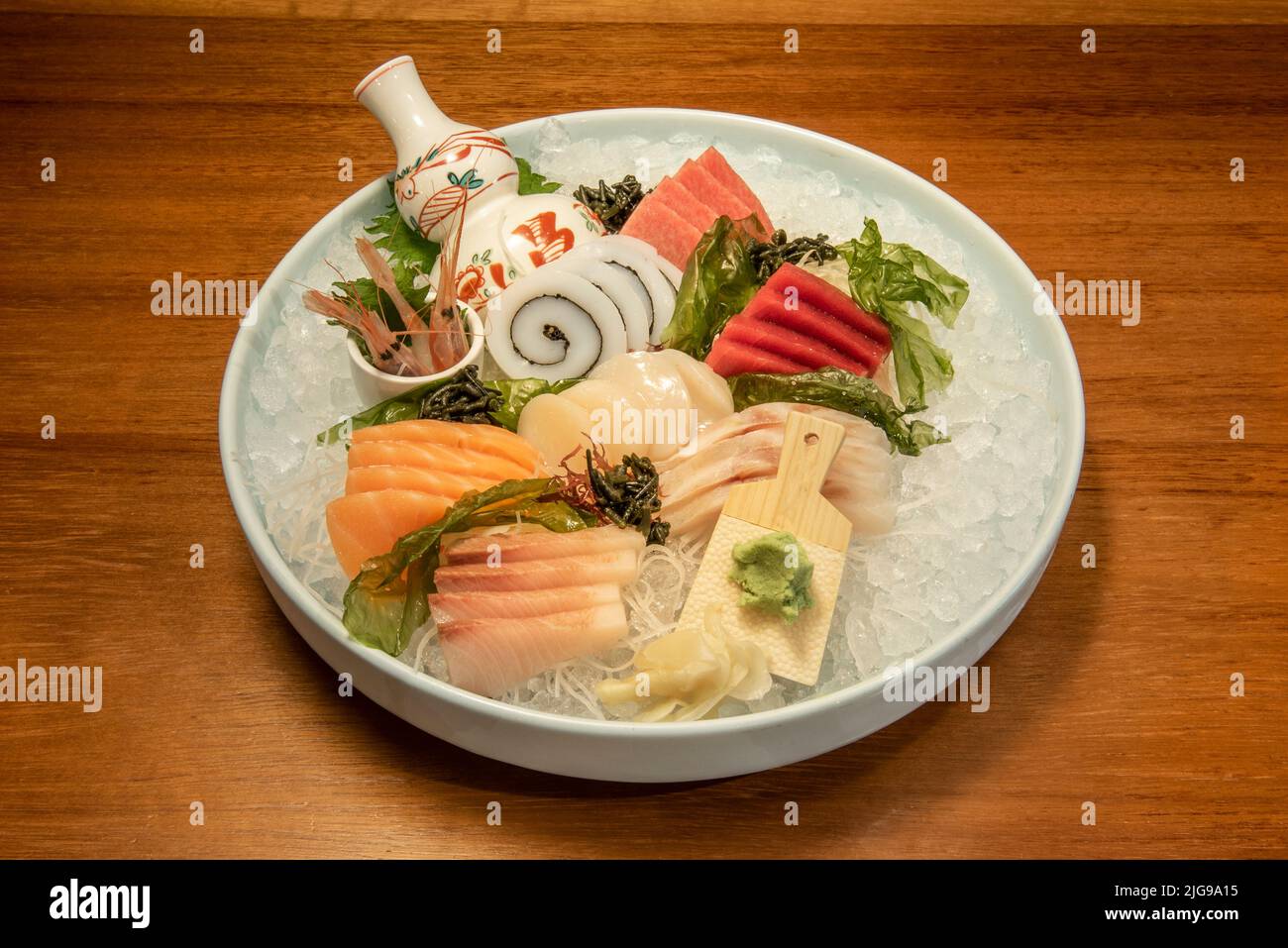 Grande vassoio di sushi di sashimi di spigola, calamari con alghe, salmone norvegese, pesce farfalla e tonno rosso pinna gialla su un sacco di ghiaccio tritato Foto Stock